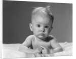1960s portrait baby lying on stomach with messy hair and bulging eyes looking at camera by Anonymous