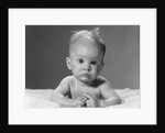 1960s portrait baby lying on stomach with messy hair and bulging eyes looking at camera by Anonymous