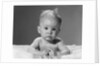 1960s portrait baby lying on stomach with messy hair and bulging eyes looking at camera by Anonymous