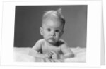 1960s portrait baby lying on stomach with messy hair and bulging eyes looking at camera by Anonymous