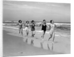 1930s four women and one man running on beach holding hands by Anonymous