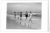 1930s four women and one man running on beach holding hands by Anonymous