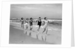 1930s four women and one man running on beach holding hands by Anonymous