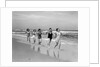 1930s four women and one man running on beach holding hands by Anonymous