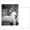 1950s little blond girl in pajamas standing at bathroom sink brushing her teeth toothpaste and toothbrush in hand by Anonymous