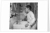 1950s boy combing hair looking in bathroom sink mirror by Anonymous