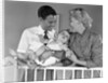 1950s smiling parents picking baby up out of crib by Anonymous