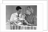 1950s smiling parents picking baby up out of crib by Anonymous