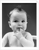 1940s thoughtful baby with finger in mouth by Anonymous