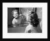 1950s girl looking in bathroom mirror brushing teeth by Anonymous