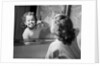 1950s girl looking in bathroom mirror brushing teeth by Anonymous
