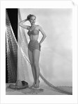 1950s glamour girl looking at camera posed in studio draped in fishing net wearing two piece bathing suit by Anonymous