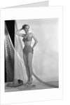 1950s glamour girl looking at camera posed in studio draped in fishing net wearing two piece bathing suit by Anonymous