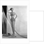 1950s glamour girl looking at camera posed in studio draped in fishing net wearing two piece bathing suit by Anonymous