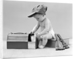 1940s baby in railroad engineer hat pulling milk bottle from lunch pail with hammer & wrench tools at side studio by Anonymous
