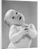 1950s baby in diaper head to one side arms hands clasped in front by Anonymous