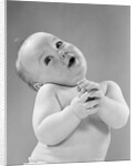1950s baby in diaper head to one side arms hands clasped in front by Anonymous