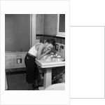 1930s boy washing face at bathroom sink by Anonymous