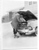 1950s man winter driveway trying to start fix car hood up by Anonymous