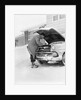 1950s man winter driveway trying to start fix car hood up by Anonymous