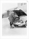 1950s man winter driveway trying to start fix car hood up by Anonymous