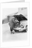 1950s man winter driveway trying to start fix car hood up by Anonymous