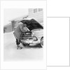 1950s man winter driveway trying to start fix car hood up by Anonymous