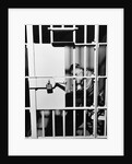 1960s man seated on bench in jail cell with head in hand looking downward by Anonymous
