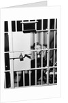 1960s man seated on bench in jail cell with head in hand looking downward by Anonymous