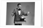 1960s man magician wearing tuxedo white rabbit peaking our of top hat by Anonymous