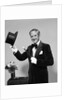 1970s smiling man magician wearing velvet tuxedo white gloves pointing magic wand at top hat looking at camera by Anonymous