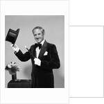1970s smiling man magician wearing velvet tuxedo white gloves pointing magic wand at top hat looking at camera by Anonymous