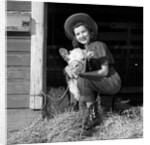 Girl posing with calf in straw filled stall in barn by Anonymous