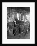 1930s elderly blacksmith with hammer at anvil as young boy holding harness looks on smiling by Anonymous