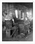 1930s elderly blacksmith with hammer at anvil as young boy holding harness looks on smiling by Anonymous