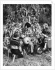 1950s boy & girl sitting in front of corn stalks watching father carve pumpkin by Anonymous