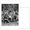 1950s boy & girl sitting in front of corn stalks watching father carve pumpkin by Anonymous