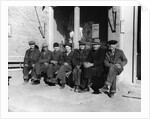 1920s 1930s group of old men in hats & dungarees sitting on bench in front of store window looking at camera by Anonymous
