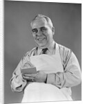 1940s man wearing white apron writing order on pad with pencil looking at camera by Anonymous
