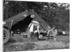 1920s couple man woman on fishing camping trip vacation at campsite man cooking over fire by Anonymous