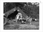 1920s couple man woman on fishing camping trip vacation at campsite man cooking over fire by Anonymous