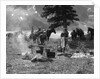 1920s 1930s two women at campsite woman cooking preparing food over campfire horses with riding gear in background by Anonymous