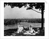 1930s 1940s family picnicking under a tree in fairmont park with skyline of philadelphia pa on horizon by Anonymous