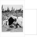 1930s smiling talking couple working by rustic western campsite tent man in cowboy hat smoking pipe washing skillet woman drying dishes by Anonymous