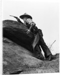 1920s cowboy among rocks aiming revolver by Anonymous