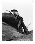 1920s cowboy among rocks aiming revolver by Anonymous