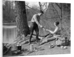 1920s 1930s man & woman camping by lake having picnic woman sitting man standing serving food to woman east creek swamp by Anonymous