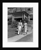 1930s couple walking out of house down sidewalk carrying picnic baskets & thermos jug by Anonymous