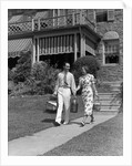 1930s couple walking out of house down sidewalk carrying picnic baskets & thermos jug by Anonymous
