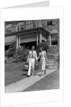 1930s couple walking out of house down sidewalk carrying picnic baskets & thermos jug by Anonymous